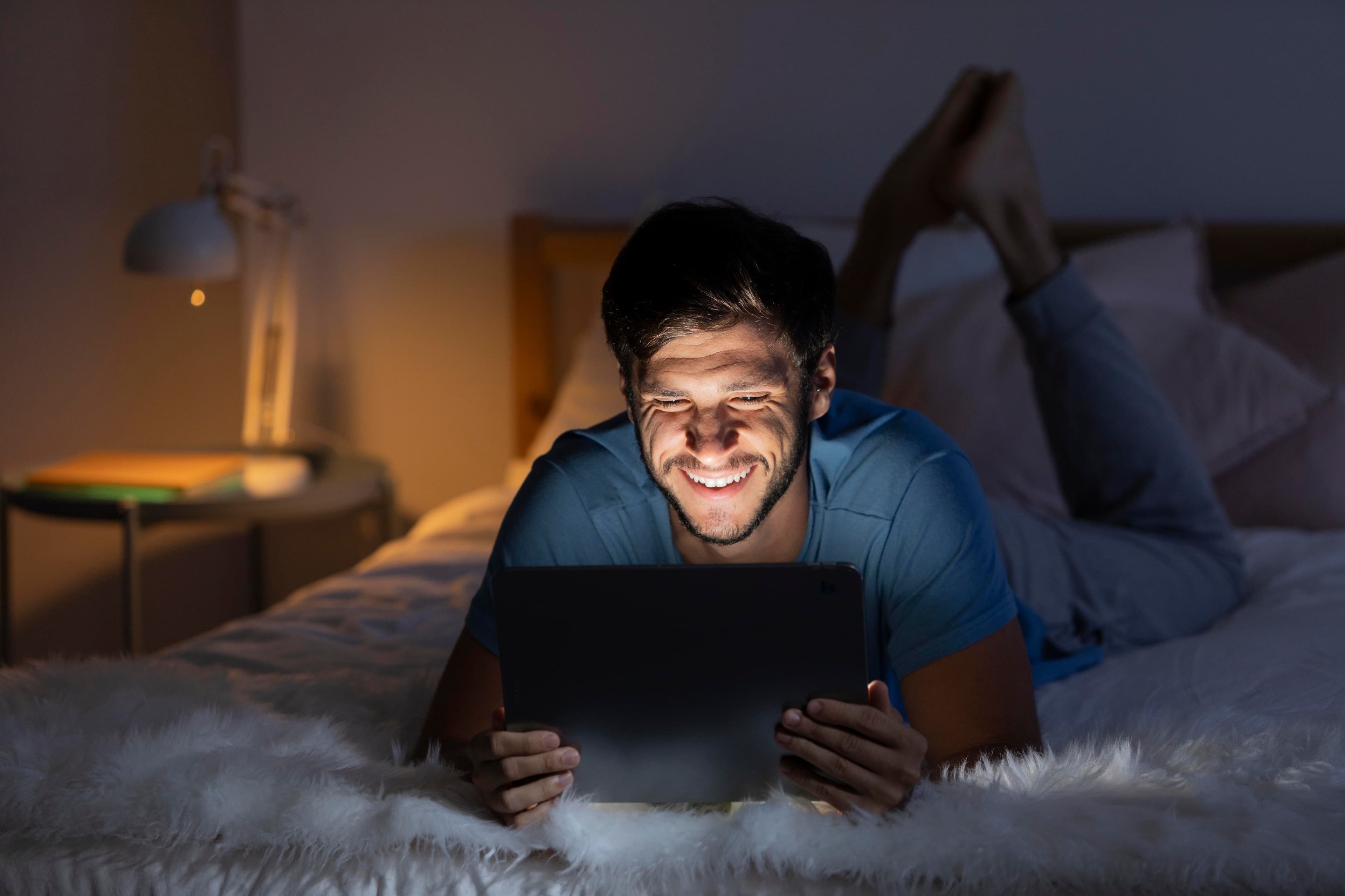 Man reading on tablet in bed